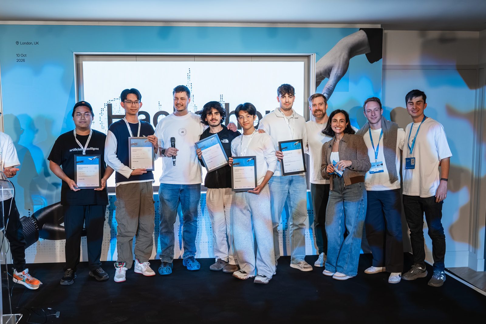 The team with their certificates in a wider group photo on stage at the prize giving